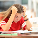 Single frustrated student girl trying to understand notes sitting in a bar