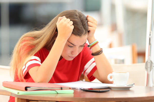 Single frustrated student girl trying to understand notes sitting in a bar